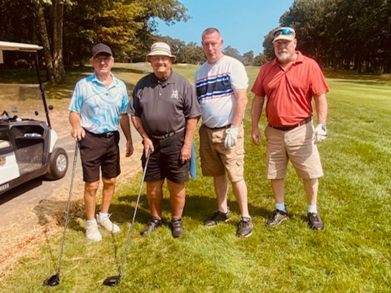 Four men standing on a golf course, ready to play.