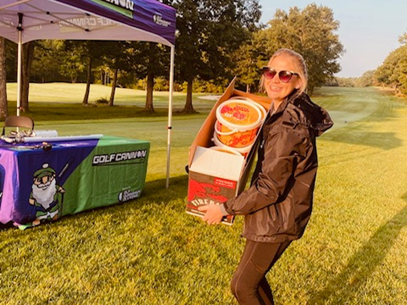 A woman holding boxes of snacks at an outdoor event.