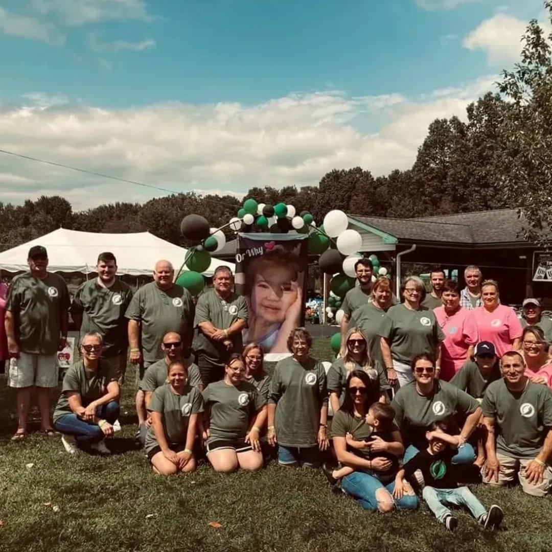 Group photo of people outdoors at a gathering with balloons and tents.